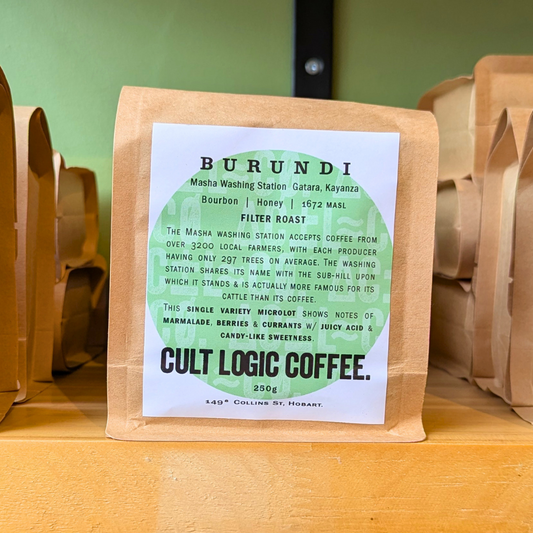 Cult Logic Coffee bag labeled 'Burundi' on a wooden shelf with a green background.